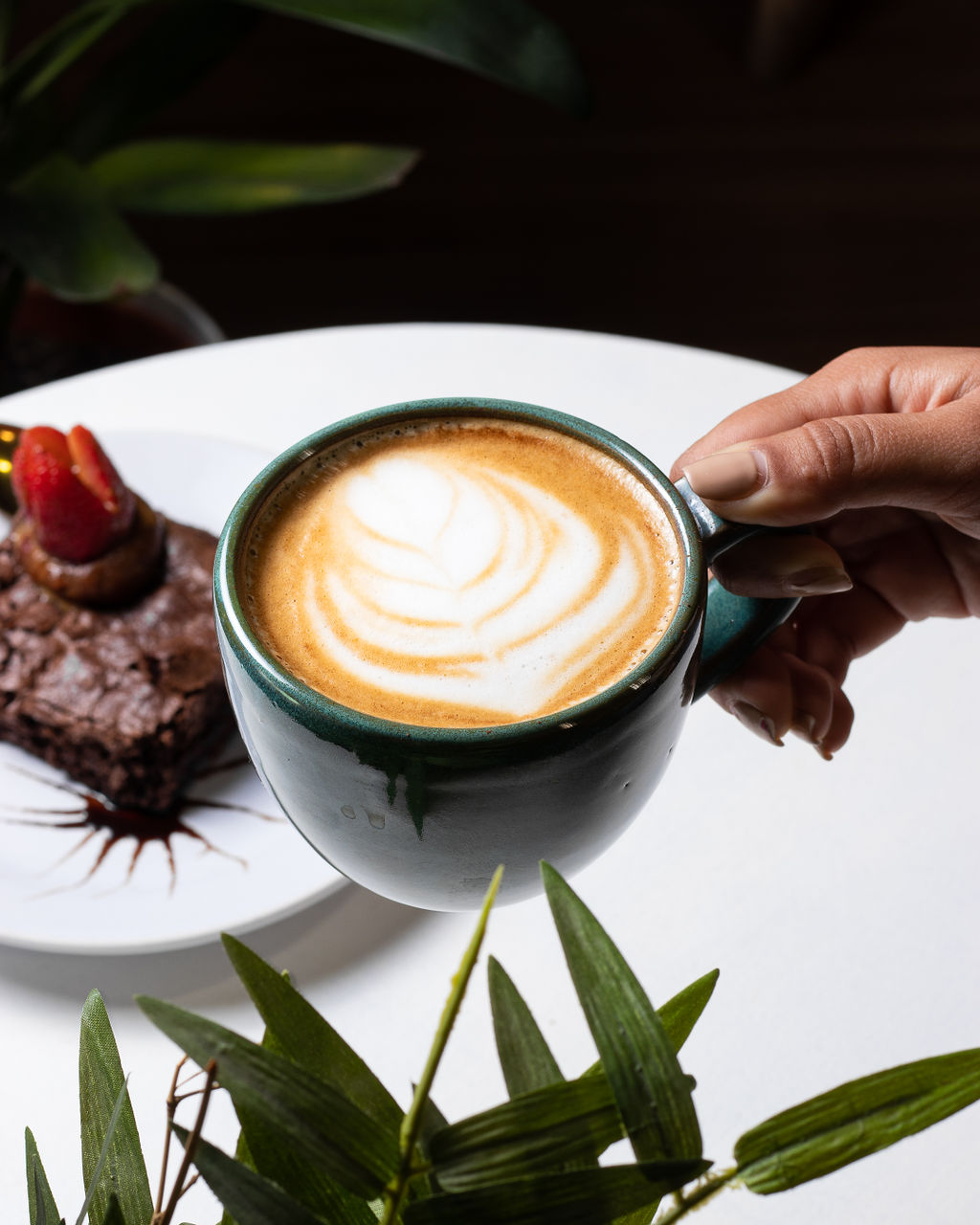 Café latte art sostenido en mano