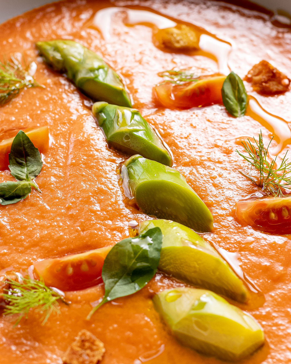 Gazpacho en bowl rojo con palta y hierbas