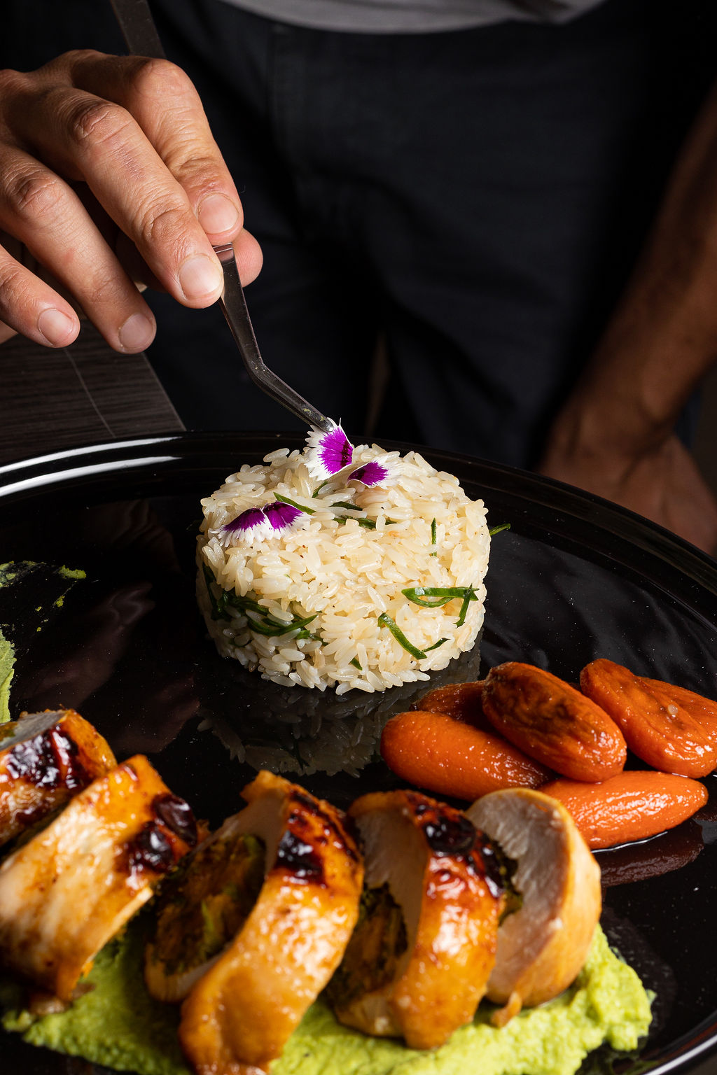 Chef coloca flor sobre arroz - manos y pinzas